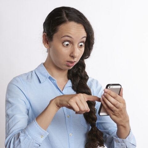 Woman staring at smartphone with shocked expression on her face
